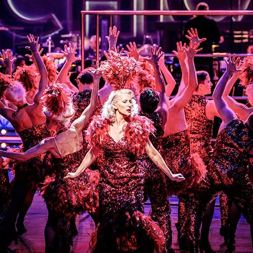 Dansande människor med glittriga, röda kläder och händerna i luften